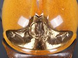 a golden vase with a face on it on a stand