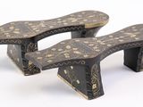 pair of black and gold painted wooden foot stools on a white background