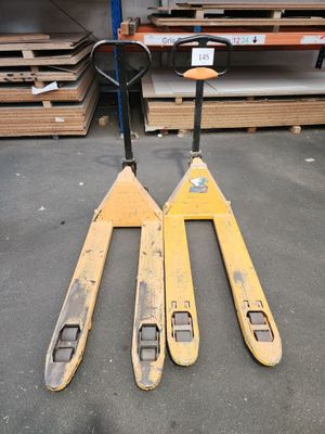 deux chariots élévateurs sont posés sur des palettes dans un entrepôt