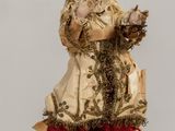 doll of a woman holding a basket of flowers on a table