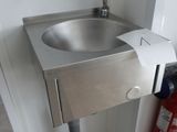 un lavabo situé dans un coin de la salle de bains, équipé d'un distributeur de serviettes en papier