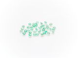 a pile of green glass beads on a white surface