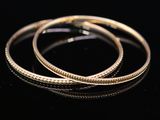 a close up of a pair of gold hoop earrings on a black surface