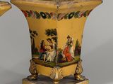 pair of yellow vases with painted scenes on them sitting on a table