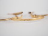 a close up of a pair of gold bracelets on a white surface