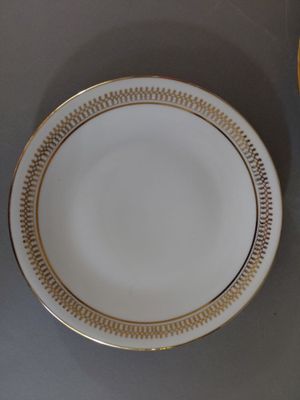 une assiette blanche bordée d’or et un bol d’oranges
