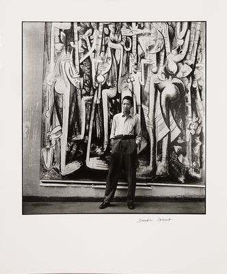 photographie en noir et blanc d'un homme debout devant un tableau