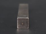 a square metal bar on a black surface