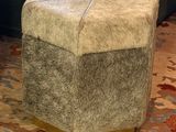 a small stool with a cow hide on it in a living room