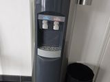 un distributeur d'eau posé par terre, à côté d'une poubelle