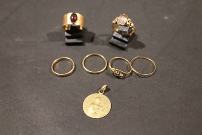trois bagues en or et une pièce d'or posées sur une table