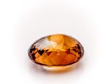 a close up of a faceted orange sapphire stone on a white surface