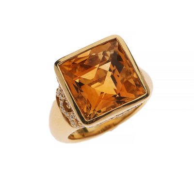 un gros plan d'une bague en or sertie d'une topaze orange