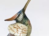 a figurine of a bird sitting on top of a leaf