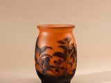 a small orange vase with a black design on it