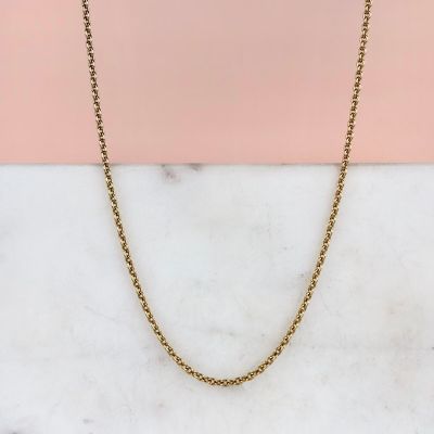 un collier à chaîne en or posé sur une surface en marbre