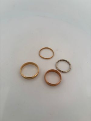 four gold wedding rings on a white surface