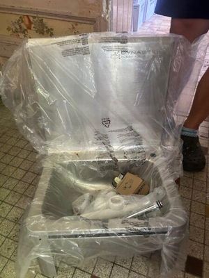 a man standing next to a piece of luggage that is wrapped in plastic