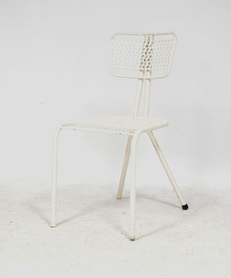 une photo d'une chaise en métal blanc devant un mur blanc