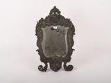 un miroir ancien posé sur un pied, sur fond blanc