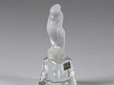une figurine en verre représentant un oiseau, posée sur un socle en verre