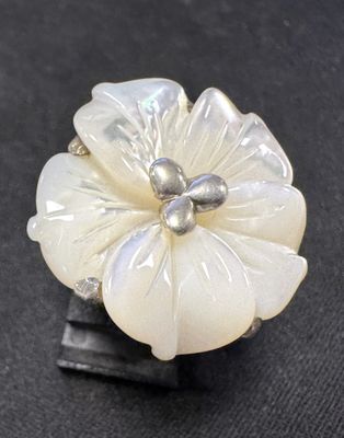 une bague en forme de fleur blanche avec une perle au centre