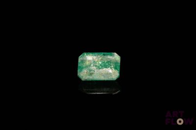 a green emerald stone on a black surface