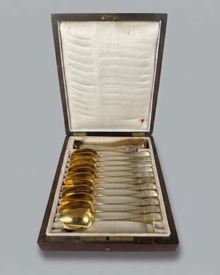 six gold spoons in a case with a silver spoon in it
