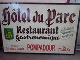 une enseigne indiquant « Hôtel du Parc, restaurant gastronomique Pompadour »