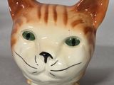 a small ceramic cat with green eyes sitting on a table
