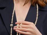 gros plan sur une femme portant un collier de perles muni d'un fermoir en diamant