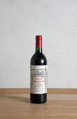 une bouteille de vin rouge posée sur une table en bois, avec un mur blanc en arrière-plan