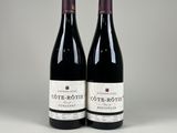 two bottles of red wine sitting next to each other on a table