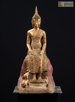 une statue en or représentant une personne assise sur un rocher avec un chien