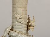 a white vase with a dragon on it on a table