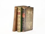 three old books are stacked on top of each other on a white surface