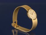 yellow gold watch on a blue surface with reflection