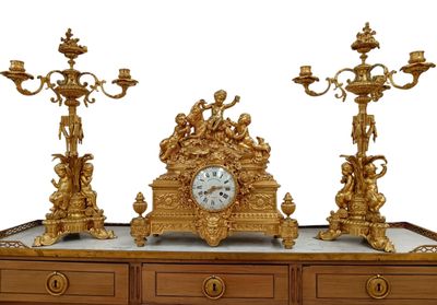 a gold clock sitting on top of a wooden table