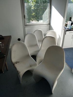 quatre chaises blanches dans une pièce avec une fenêtre en arrière-plan
