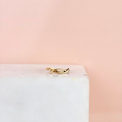 un gros plan d'une bague en or posée sur un bloc de marbre