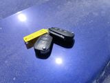 two car keys on a blue table with a yellow tag