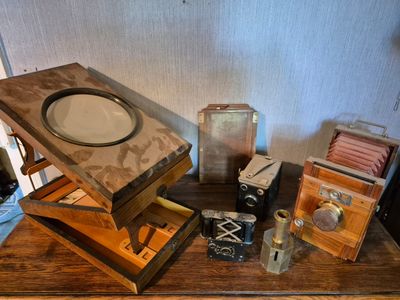 a wooden table with a lot of old cameras on it