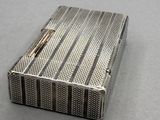un vieux étui à cigarettes en argent posé sur une table