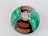 a green and black ball sitting on a white surface