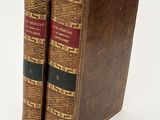 two old books sitting on top of each other on a white surface