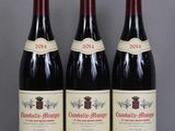 three bottles of red wine are lined up on a table
