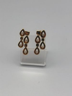une paire de boucles d'oreilles en or et diamants posée sur un présentoir transparent