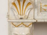a white marble fireplace with a gold decoration on it