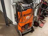 an orange and black machine sitting in a garage next to other equipment