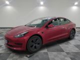 une Tesla Model 3 rouge garée sur un sol à damier